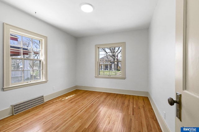 empty room featuring wood finished floors, baseboards, and visible vents