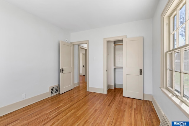unfurnished bedroom with visible vents, baseboards, and light wood-type flooring