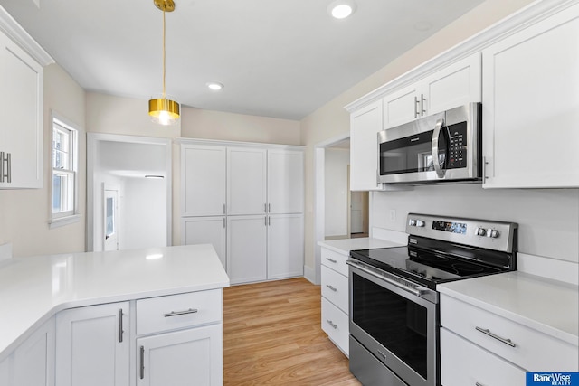 kitchen with pendant lighting, light wood-style flooring, white cabinetry, appliances with stainless steel finishes, and light countertops