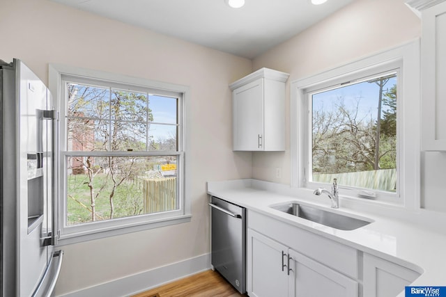 kitchen featuring light countertops, appliances with stainless steel finishes, a sink, and plenty of natural light