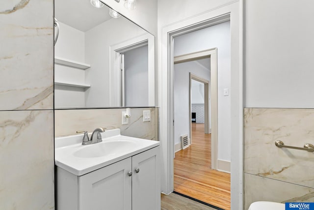bathroom with vanity, visible vents, baseboards, and wood finished floors