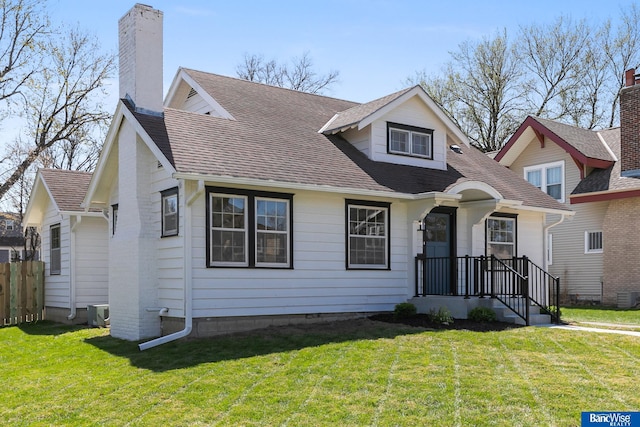 bungalow-style home featuring a chimney, a shingled roof, and a front yard