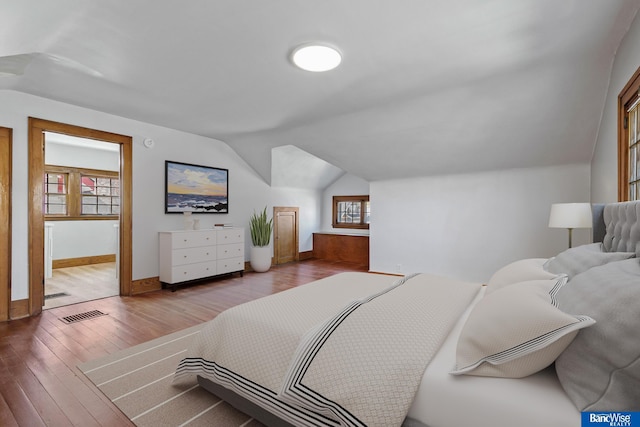 bedroom with baseboards, visible vents, vaulted ceiling, and hardwood / wood-style floors