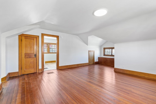 additional living space featuring visible vents, hardwood / wood-style flooring, baseboards, and lofted ceiling