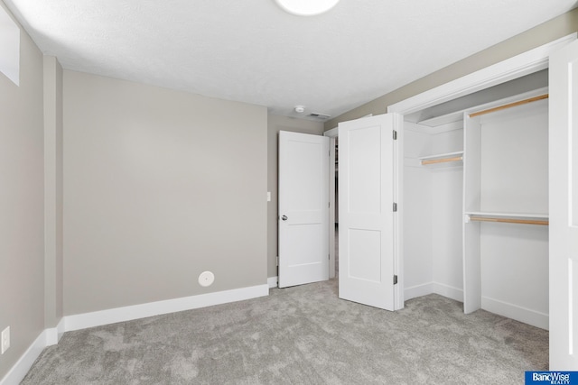 unfurnished bedroom with a textured ceiling, a closet, baseboards, and carpet