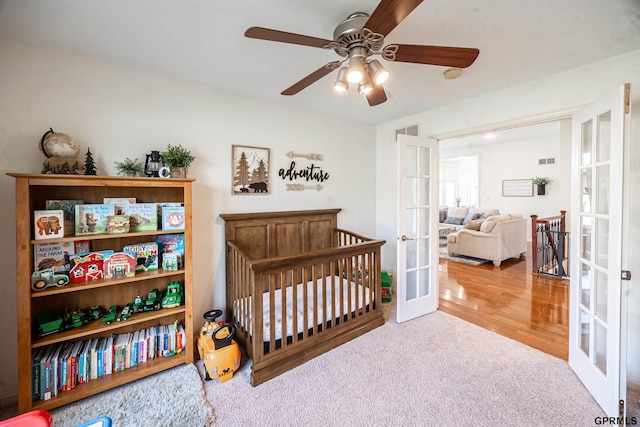 bedroom with french doors, carpet flooring, visible vents, ceiling fan, and a crib