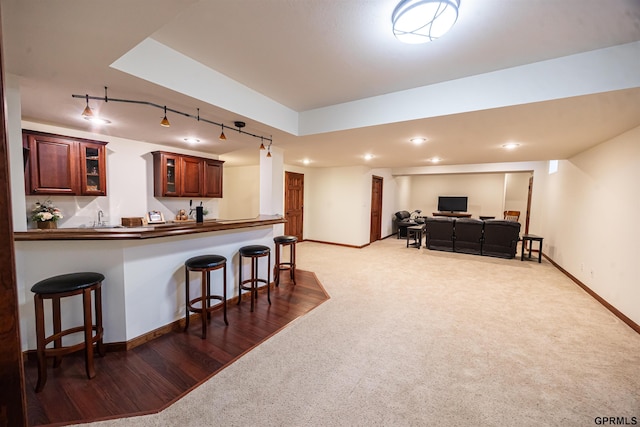 kitchen with a kitchen bar, baseboards, dark countertops, and glass insert cabinets