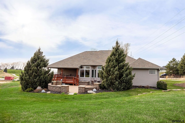 rear view of property featuring a patio area, a lawn, and a shingled roof