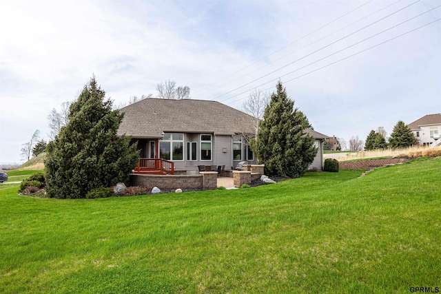 rear view of house with a patio area, roof with shingles, and a yard