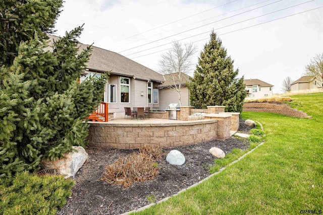 exterior space with a lawn, a shingled roof, area for grilling, and a patio