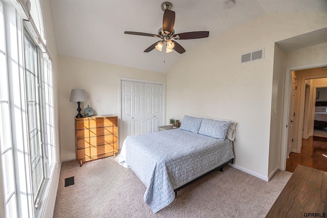 carpeted bedroom with lofted ceiling, visible vents, a closet, baseboards, and ceiling fan