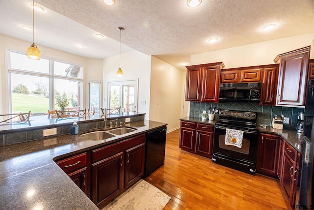 kitchen with backsplash, dark brown cabinets, a sink, pendant lighting, and black appliances