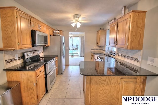 kitchen with a sink, ceiling fan, appliances with stainless steel finishes, and decorative backsplash