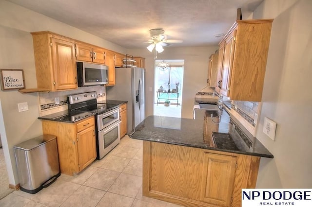 kitchen featuring dark stone counters, stainless steel appliances, light tile patterned floors, ceiling fan, and tasteful backsplash