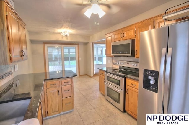 kitchen featuring a ceiling fan, a peninsula, stainless steel appliances, and decorative backsplash