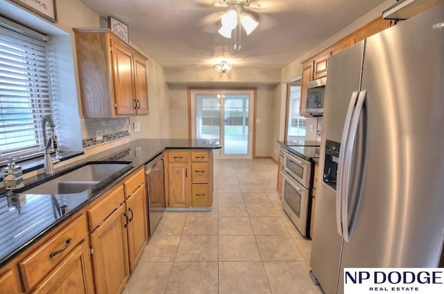 kitchen with tasteful backsplash, a sink, ceiling fan, stainless steel appliances, and a peninsula