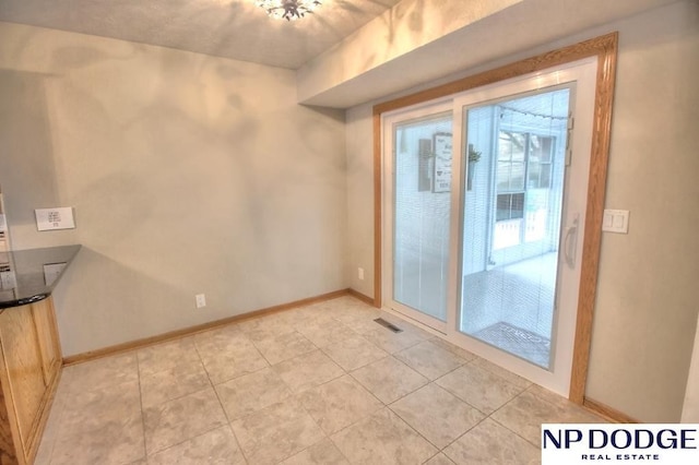 spare room with baseboards, visible vents, and light tile patterned floors