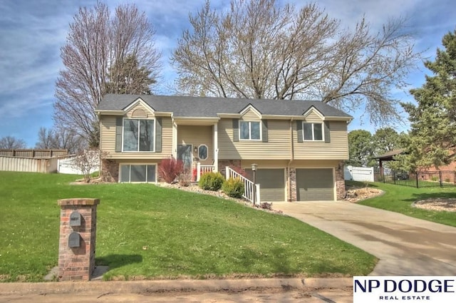 bi-level home with a front yard, a garage, driveway, brick siding, and fence