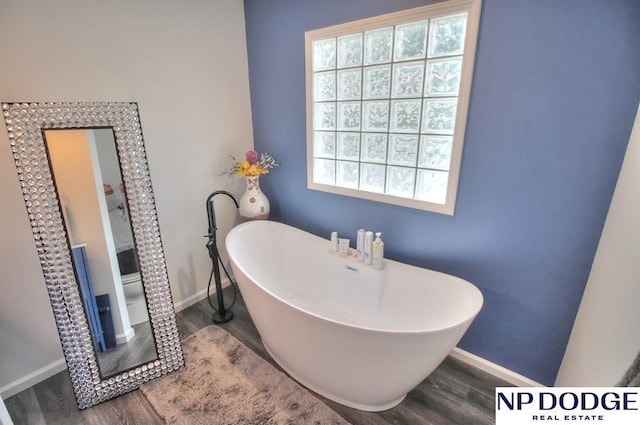 full bathroom with baseboards, a freestanding tub, and wood finished floors