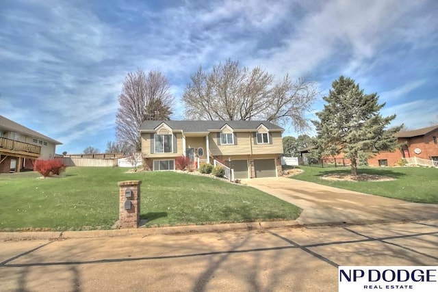 split foyer home featuring concrete driveway, a garage, a front lawn, and fence