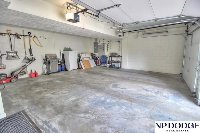 garage with concrete block wall, electric panel, and a garage door opener