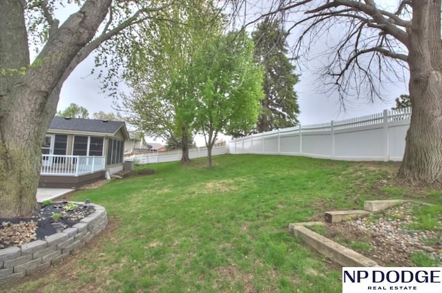 view of yard featuring a sunroom and a fenced backyard
