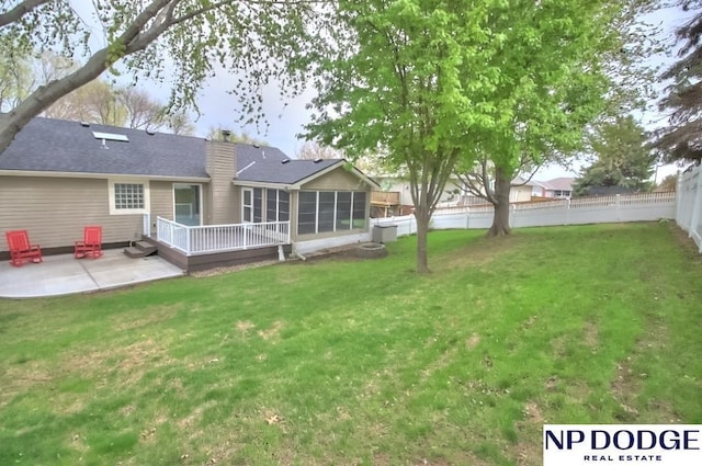 view of yard with a sunroom, a wooden deck, a patio, and a fenced backyard