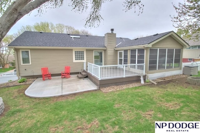 back of house featuring a patio, a deck, a chimney, a lawn, and a sunroom