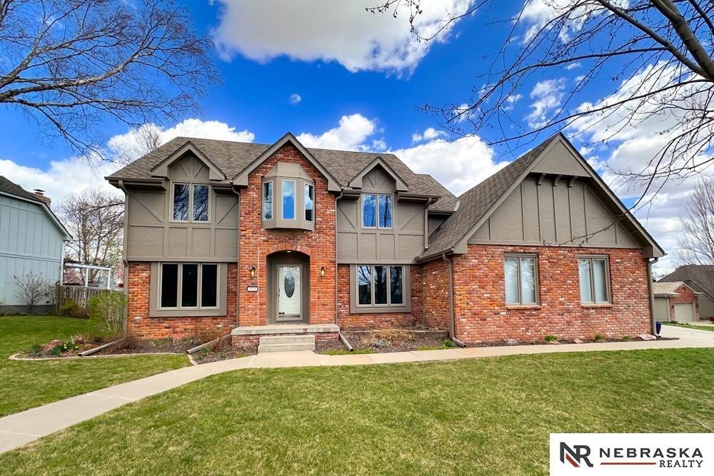 view of front of property with a front yard, a shingled roof, and brick siding