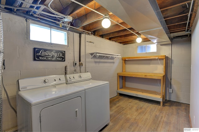 laundry room featuring washer and clothes dryer, light wood-style flooring, laundry area, and a healthy amount of sunlight