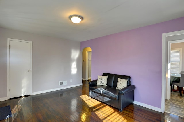 interior space featuring arched walkways, visible vents, baseboards, and hardwood / wood-style floors