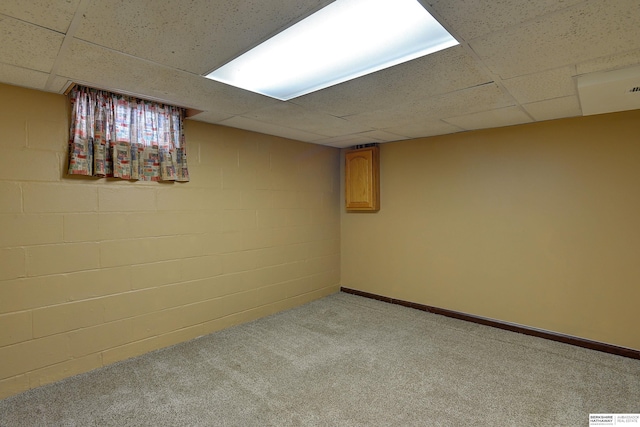 finished below grade area featuring carpet flooring, a paneled ceiling, baseboards, and concrete block wall