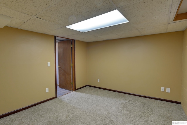 empty room featuring carpet floors, baseboards, and a paneled ceiling