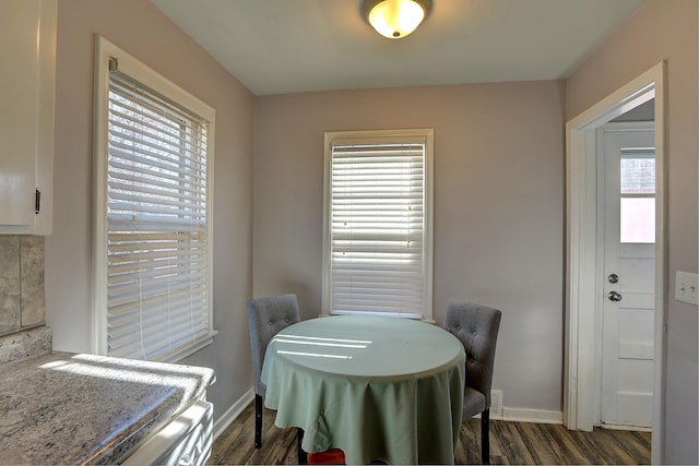 dining space featuring dark wood-style flooring and baseboards