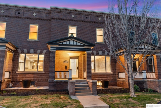 multi unit property with brick siding and a porch