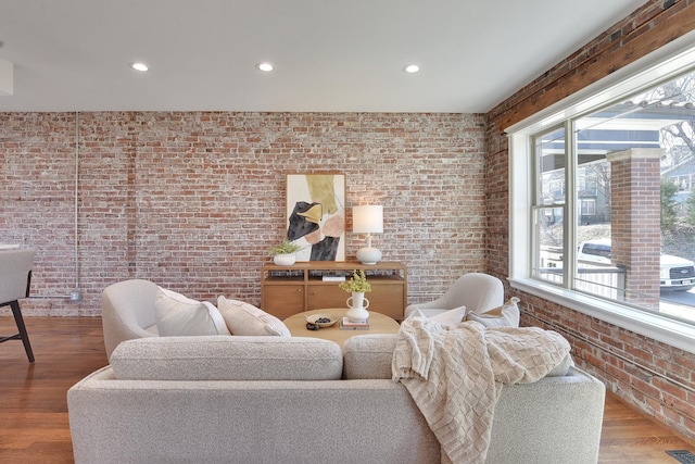 living room with brick wall, recessed lighting, and wood finished floors