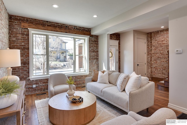 living room featuring brick wall, a healthy amount of sunlight, and wood finished floors
