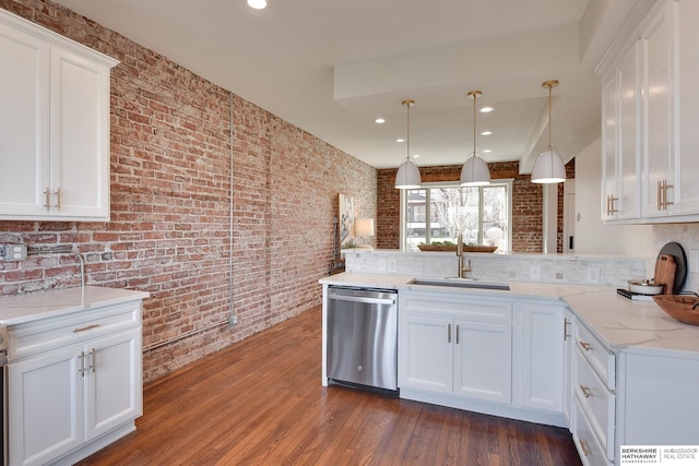 kitchen featuring light stone countertops, a peninsula, white cabinetry, dishwasher, and a sink
