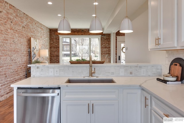 kitchen with brick wall, white cabinets, light stone countertops, dishwasher, and a sink