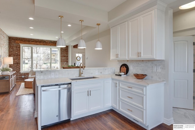 kitchen with tasteful backsplash, a peninsula, white cabinets, dishwasher, and a sink