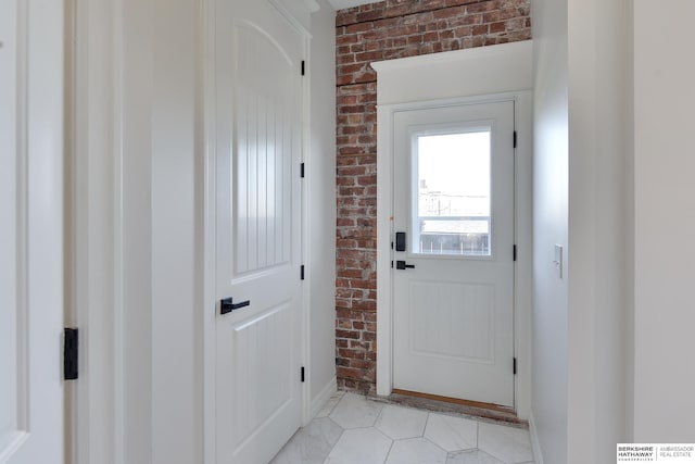 doorway featuring light tile patterned floors and brick wall