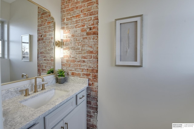 bathroom featuring brick wall and vanity