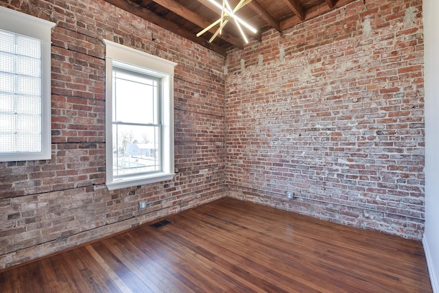 empty room with wood ceiling, brick wall, beamed ceiling, and dark wood-style floors