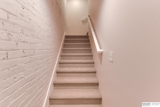 staircase featuring brick wall