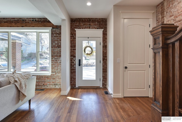 entrance foyer featuring brick wall, visible vents, baseboards, and wood finished floors