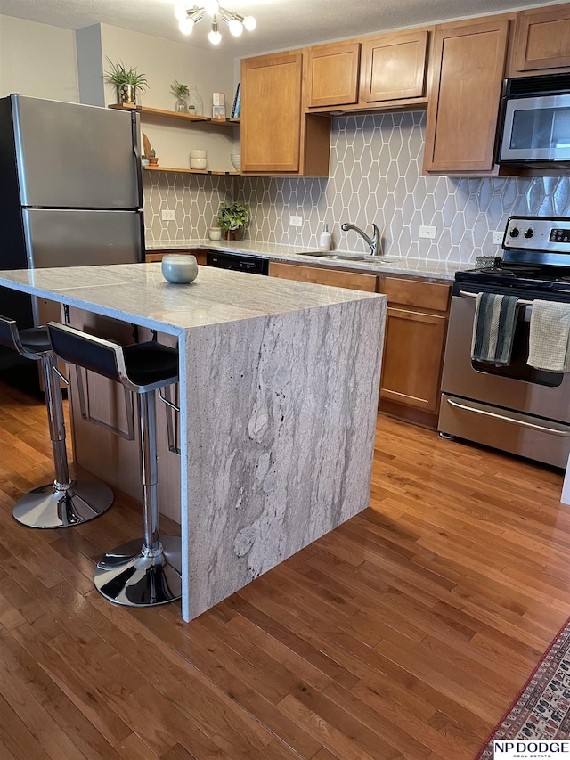 105 N 31st Ave Unit 607, Omaha, NE 68131 - kitchen with a center island, a sink, appliances with stainless steel finishes, light wood-style flooring, and light stone counters