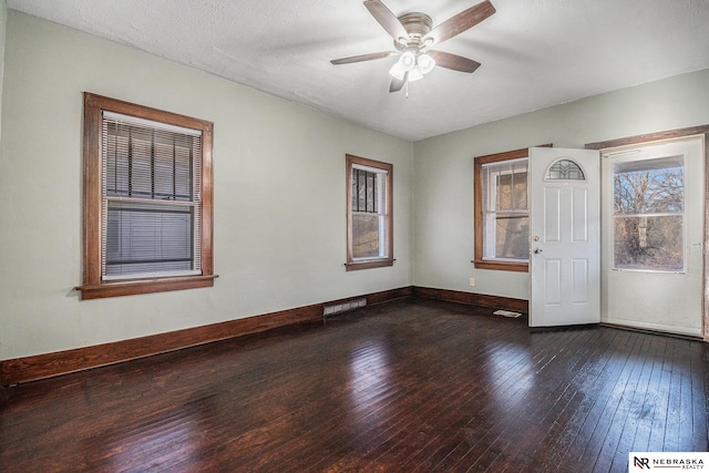 unfurnished room with dark wood-style flooring, baseboards, a ceiling fan, and visible vents