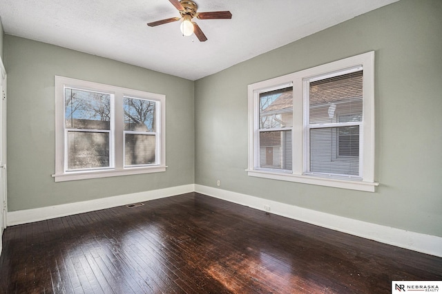 unfurnished room with ceiling fan, dark wood finished floors, visible vents, and a wealth of natural light
