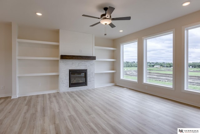 11014 N 161st St, Bennington, NE 68007 - unfurnished living room with a stone fireplace, baseboards, light wood-style floors, and a healthy amount of sunlight