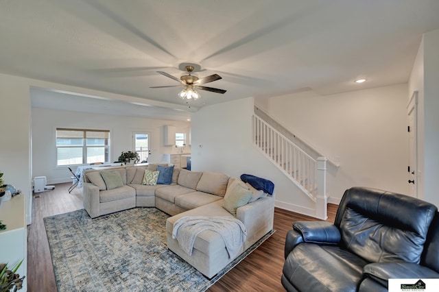 living room featuring wood finished floors, ceiling fan, baseboards, and stairs